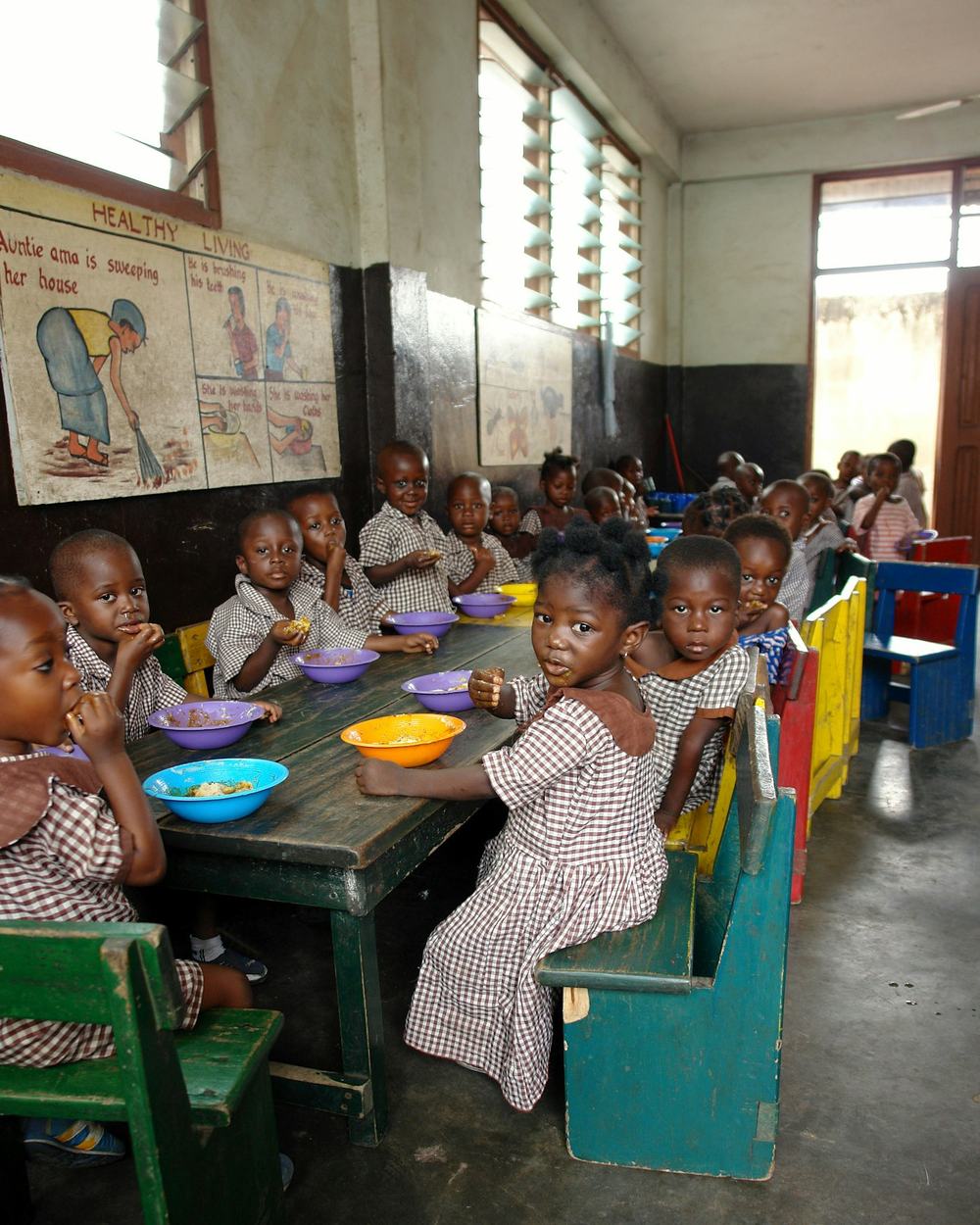 Kinderen eten samen aan lange tafels in een schoollokaal